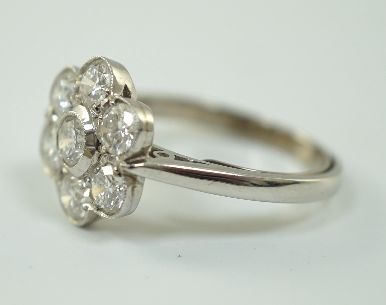 A platinum and seven stone diamond cluster set flower head ring